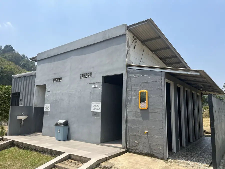 Bangunan toilet dan kamar bilas bercat abu-abu dengan wastafel di luar